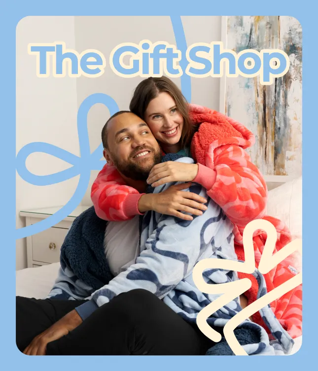 The Gift Shop: a couple cuddling under an Oodie blanket, framed by a ribbon
