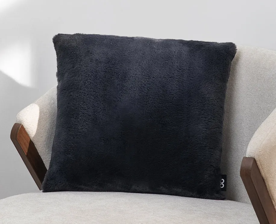 A plush black Cushion Case on an armchair