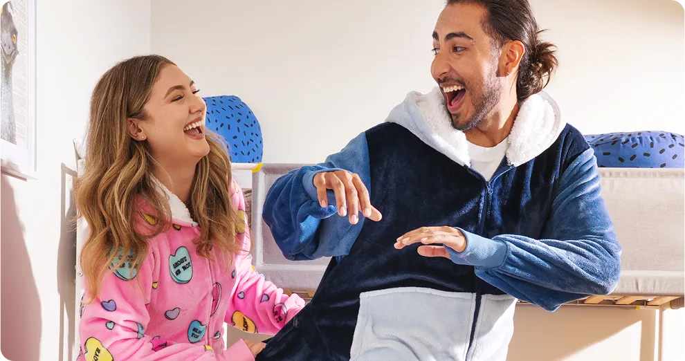 Two friends laughing together, one in a pink Oodie and one in a navy Oodie