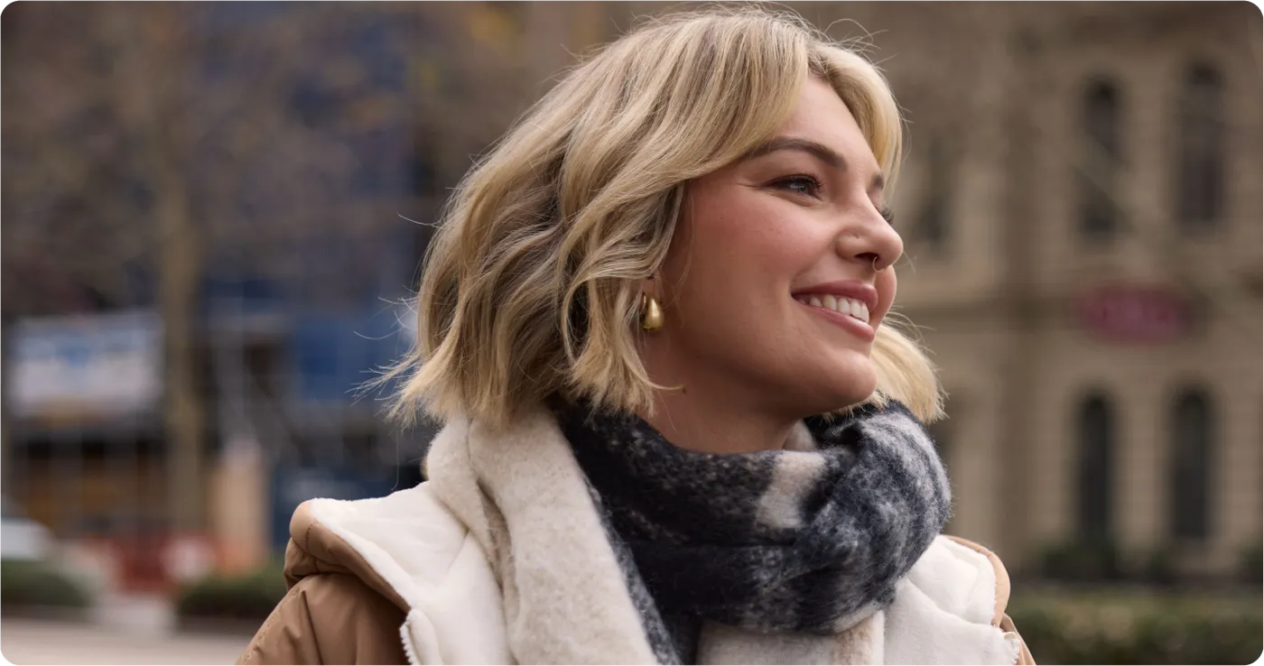 Smiling woman outdoors in a cream jacket and a soft scarf